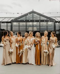 a group of women standing next to each other wearing dresses and holding bouquets in their hands