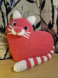 a crocheted heart shaped animal sitting on top of a wooden table next to a pillow