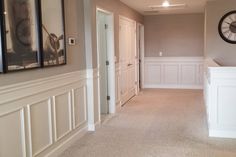 an empty hallway in a home with white wains and beige walls, two clocks on the wall