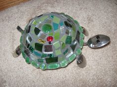 a turtle made out of glass and spoons on the floor