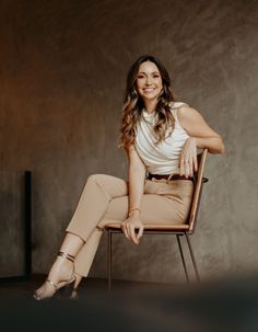 a woman sitting in a chair with her legs crossed on the ground and smiling at the camera