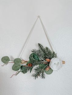 a white flower and greenery hanging on a wall