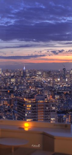 the city skyline is lit up at night with bright lights in the foreground and clouds in the background