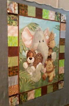 an elephant, tiger and other stuffed animals on a quilted wall hanging in a room