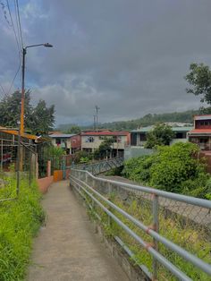 a walkway leading to some houses on a cloudy day