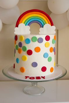 a birthday cake decorated with rainbows and clouds