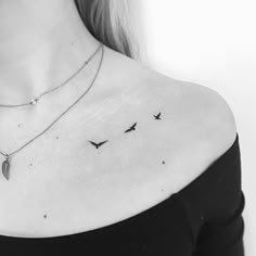 a woman's shoulder with three birds flying in the sky on her left side