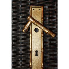 a golden door handle with two wooden handles on the front and back of it, against a wicker wall