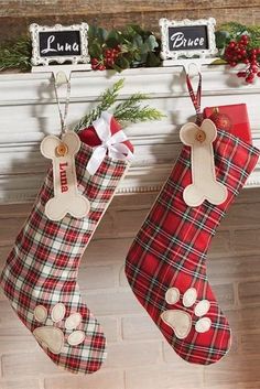 two christmas stockings hanging from a mantel decorated with plaid fabric and dog bone tags