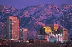 a city with mountains in the background at night, lit up by lights and snow