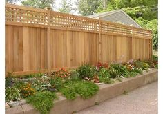 a wooden fence surrounded by flowers and plants