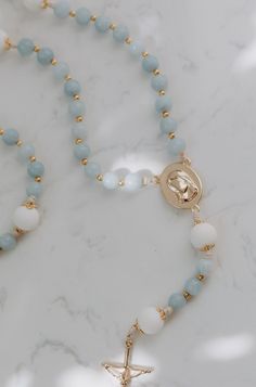 Inspired by the beloved apparitions of Our Lady of Medjugorje that still continue to this day. In her apparitions she revealed herself to be the Queen of Peace. The soft baby blues, and pure whites in this dreamy rosary brings out the truest most motherly, most Marian feel, just as the visionaries describe her as. With little gold accents and bead caps that resemble a crown, the details of this rosary exemplify the true queenship of Mary. Our Lady Queen of Peace, pray for us. Shop the entire Mat Dainty Christian Necklace, Mother Mary Bracelet, White Spiritual Rosary With Miraculous Medal, Spiritual White Rosary With Miraculous Medal, Rosary Drawing, Our Lady Queen Of Peace, Rosary Holder, Room Frames, Our Lady Of Medjugorje