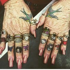 two hands with tattoos and rings on them