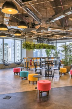 an office with chairs, tables and plants in the middle of the room that overlooks cityscape