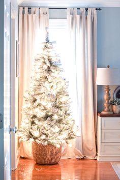 a white christmas tree sitting in front of a window