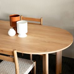 a wooden table with two white vases on it and a chair next to it