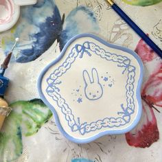 a blue and white plate sitting on top of a table next to paintbrushes