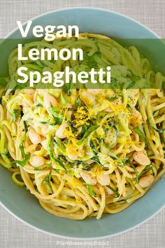 a blue bowl filled with pasta and veggies on top of a white table