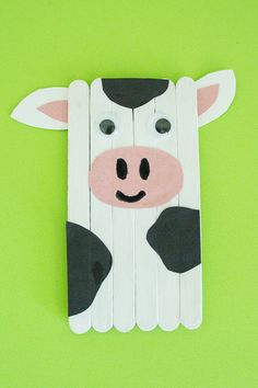 a cow made out of pops sticks on a green background