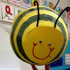 a person holding up a paper plate with a smiling bee on it's face