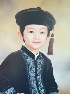 a young boy wearing a black hat with tassels on it's head