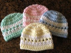 three crocheted hats sitting on top of a brown table next to each other