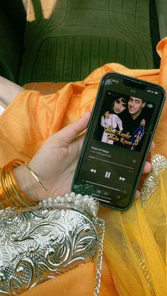 a person holding a cell phone in their hand with an mp3 player on the screen