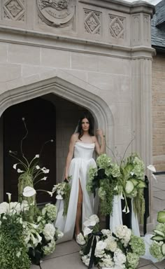 a woman in a white dress standing next to flowers