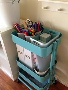 a blue cart filled with office supplies on top of a hard wood floor