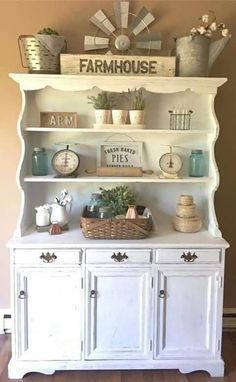 a white hutch with some plants and other items on it's top shelf