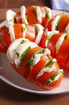 tomatoes and mozzarella are arranged on a white plate