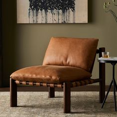 a brown leather chaise lounge chair sitting in front of a painting