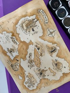 a map is shown on a piece of paper next to some watercolors and paintbrushes