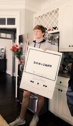 a man sitting on top of a kitchen counter holding a sign