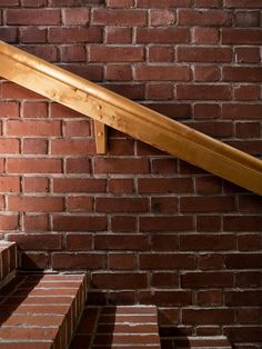 a wooden hand rail on the side of a brick wall