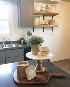 a kitchen with a sink, counter top and shelves on the wall above it is also a potted plant