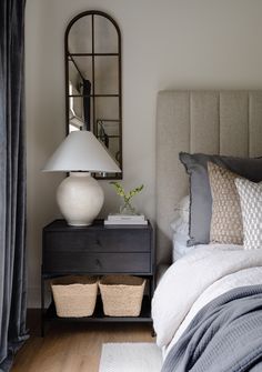 a bed room with a neatly made bed and a mirror on the wall above it