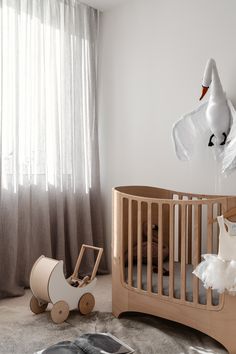 a baby's room with a crib, rocking horse and swan decoration on the wall