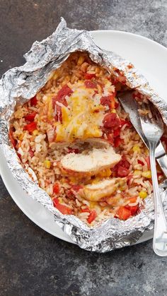 a white plate topped with chicken and rice covered in foil