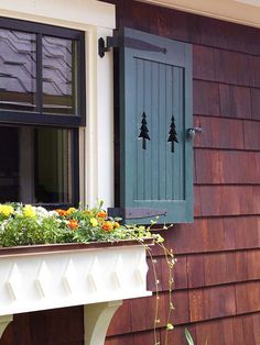 an image of a window with green shutters and flowers in the planter box