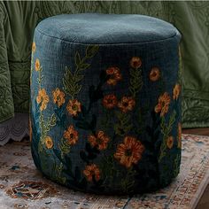 a blue ottoman sitting on top of a rug next to a green jacket and pillow