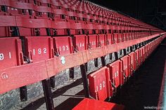 rows of empty red seats in the stands at a baseball game, with numbers painted on them