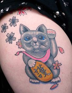 a woman's thigh with a tattoo of a cat holding an orange frisbee