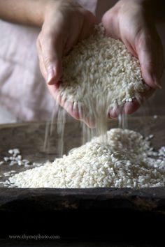 someone is sprinkling rice on top of a table