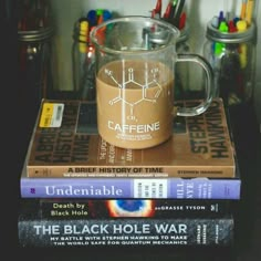 three books stacked on top of each other next to a glass mug filled with liquid