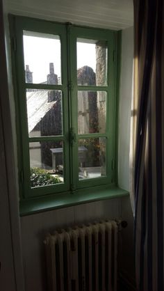 an open window in a room with a radiator next to it and a striped curtain