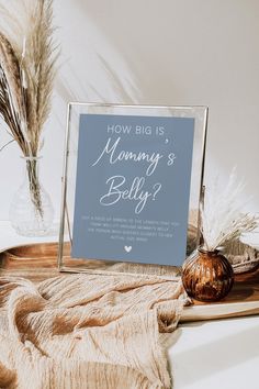 there is a sign on the table next to some feathers and a vase with flowers