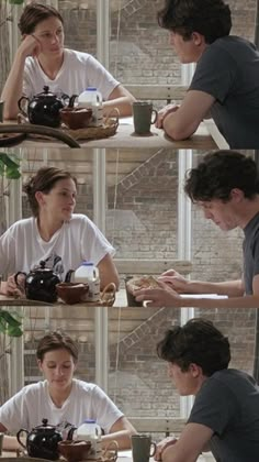 two people sitting at a table in front of a window with coffee mugs on it