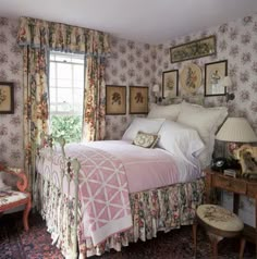 a bed sitting in a bedroom next to a window filled with curtains and pictures on the wall