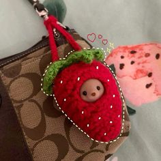 a handbag with a stuffed strawberry on the front and a small doll in the back